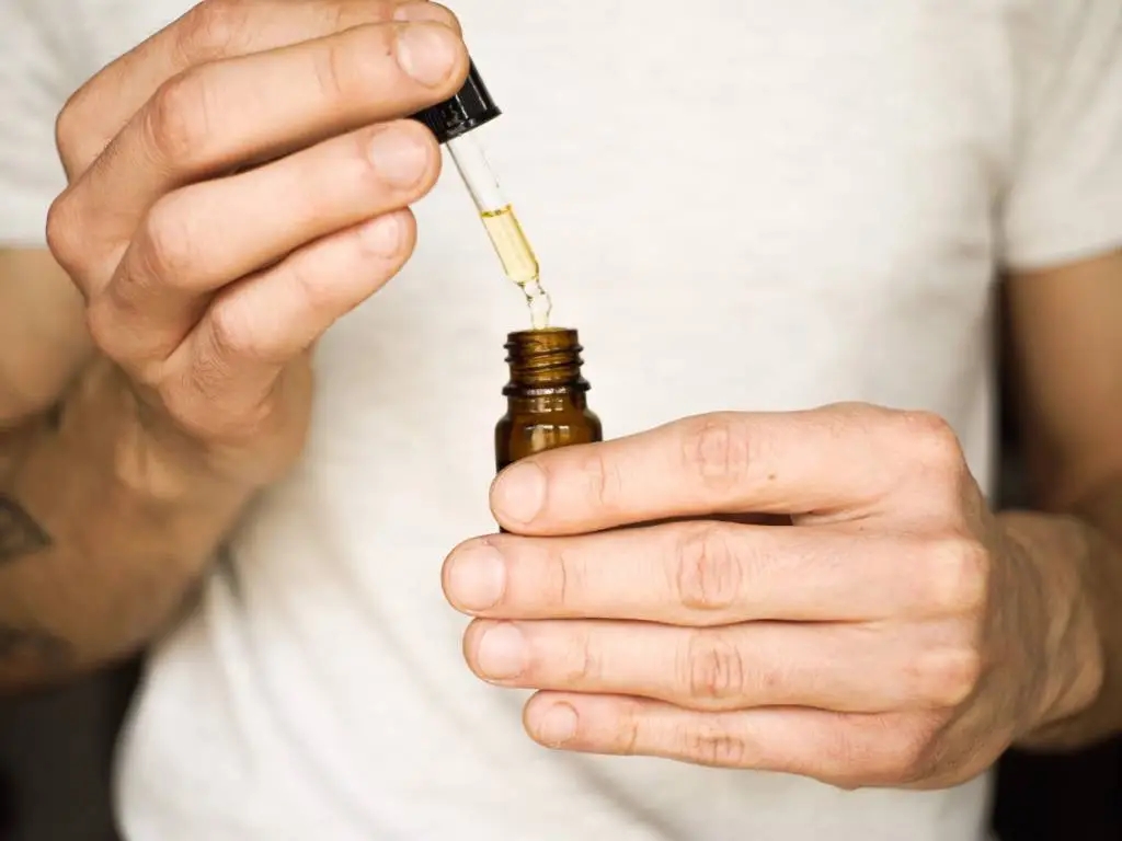 person holding dropper with CBD oil.