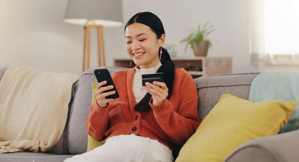 woman using credit card to make purchase on her phone